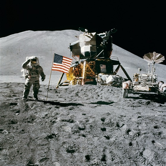Apollo astronaut saluting American flag beside lunar module photograph
